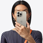 Suratının önünde iPhone 15 Pro Max tutan bir insan görseli